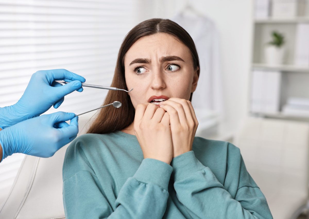 Dental phobia. Dentist working with scared woman in clinic, closeup