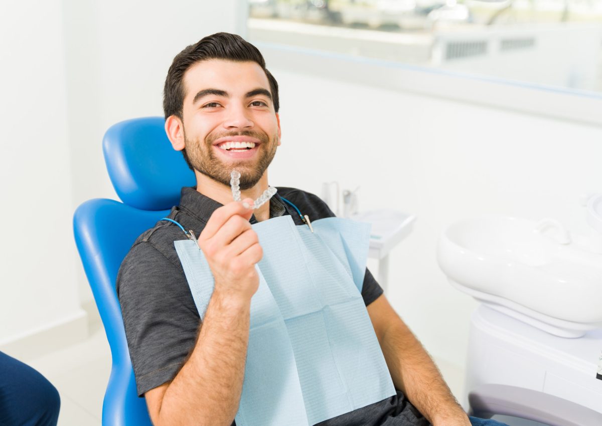 Cheerful attractive young man smiling looking happy with te results of his invisible orthodontics at the dentist