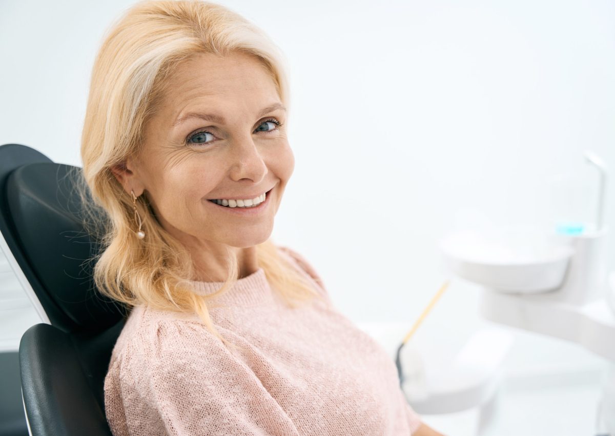 Portrait of happy woman sitting at dental chair and waiting for procedure