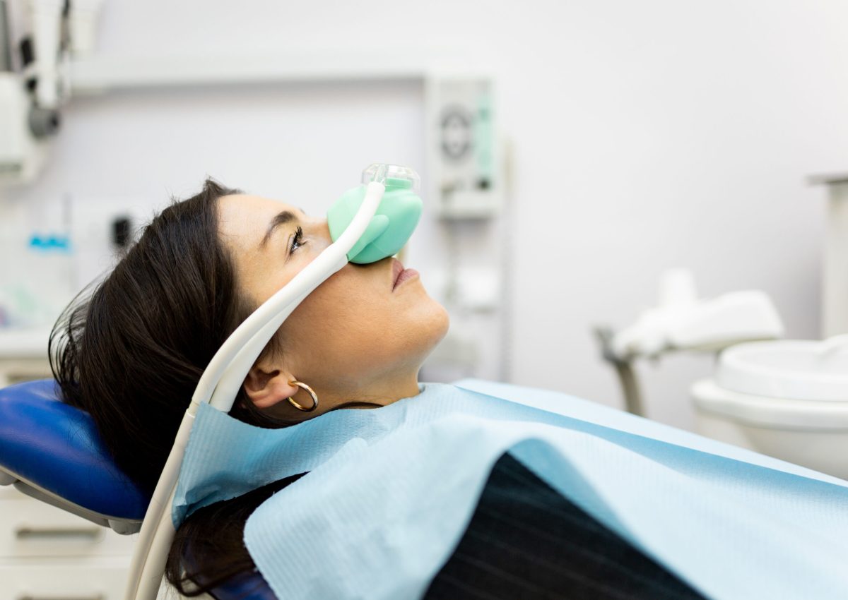An adult woman sits in a dentist's office wearing a nasal mask to inhale nitrous oxide. Dentist fear concept. Feeling of relaxation with laughing gas. Visit a dentist with relaxation.